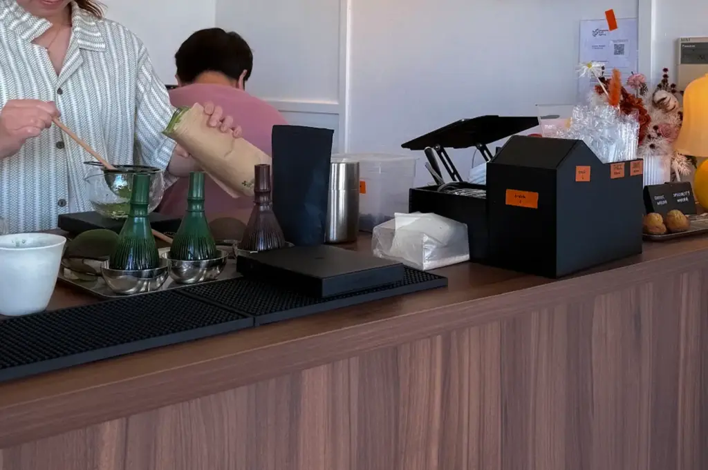 Moof Singapore cafe counter with a barista preparing matcha drinks, matcha tools, wooden cabinetry, and minimalist interior decor