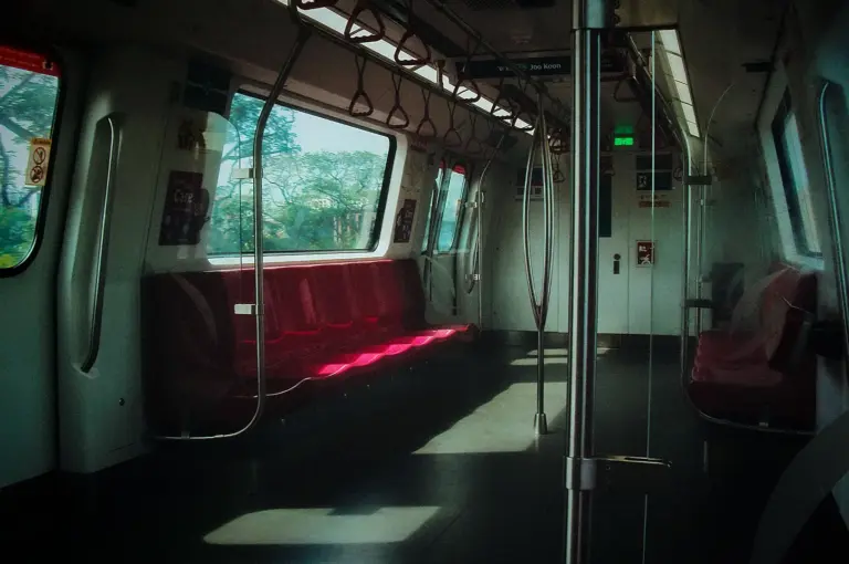 Interior of an empty Singapore MRT train carriage with red seating and large viewing windows