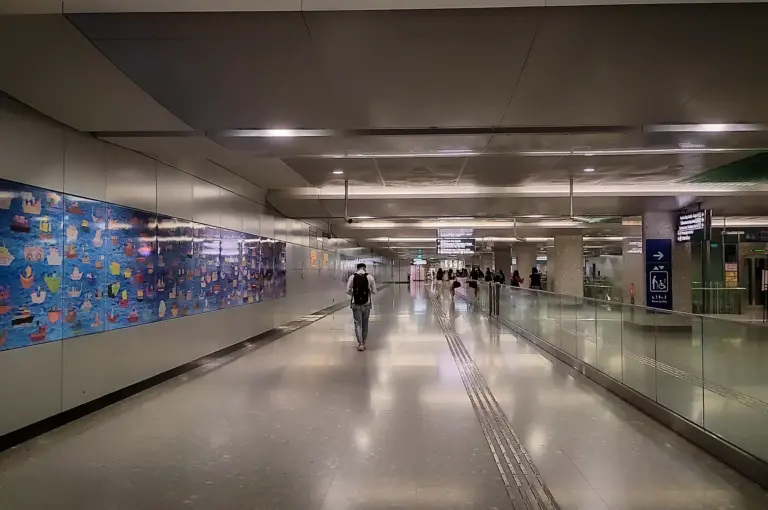 Bayfront MRT station interior in Singapore with a spacious underground concourse, directional signs, tiled flooring, and colorful wall artwork.