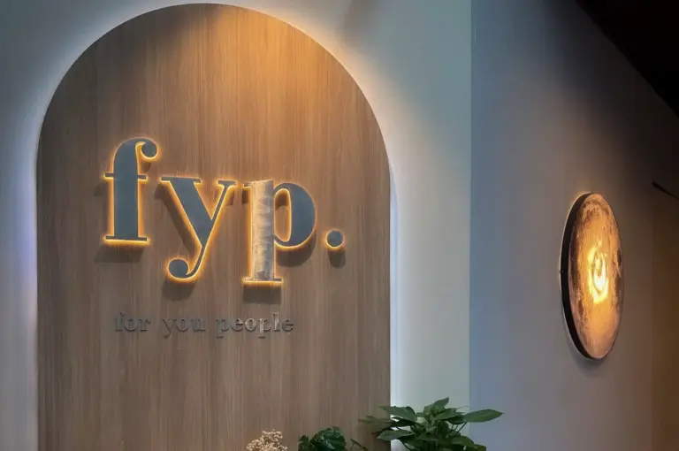 FYP Cafe Orchard Road Singapore entrance with illuminated FYP signage, a minimalist reception counter, and indoor plants.
