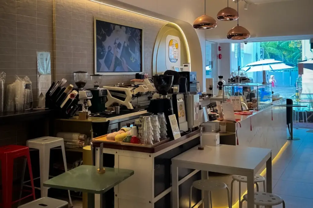 ASK Coffee Roastery Singapore interior featuring coffee machines, grinders, cafe seating, pendant lights, and a modern coffee bar setup