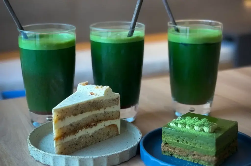 Three iced matcha green tea drinks alongside slices of layer cake and matcha cake at Hvala 111 Somerset.