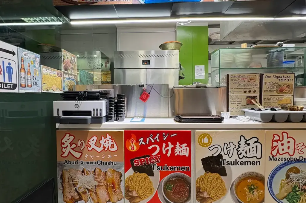 Morinaga Izakaya Singapore restaurant interior with Japanese menu displays featuring tsukemen, chashu, dashi maki tamago, and other signature dishes.