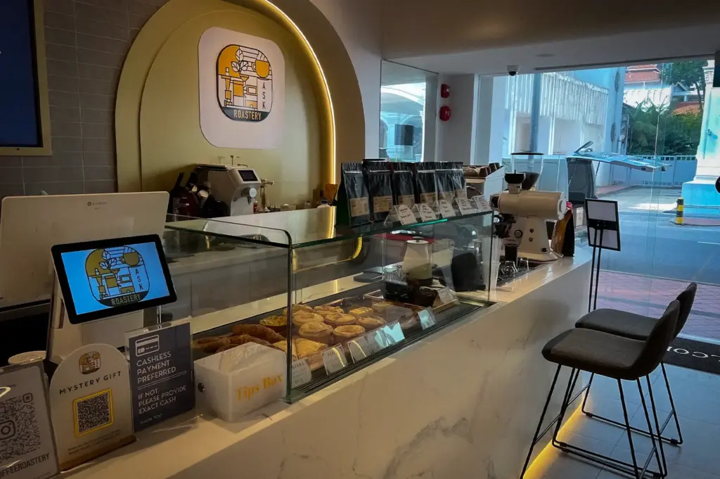 ASK Coffee Roastery Singapore coffee bar with coffee beans, espresso equipment, pastries, modern counter, and cafe seating