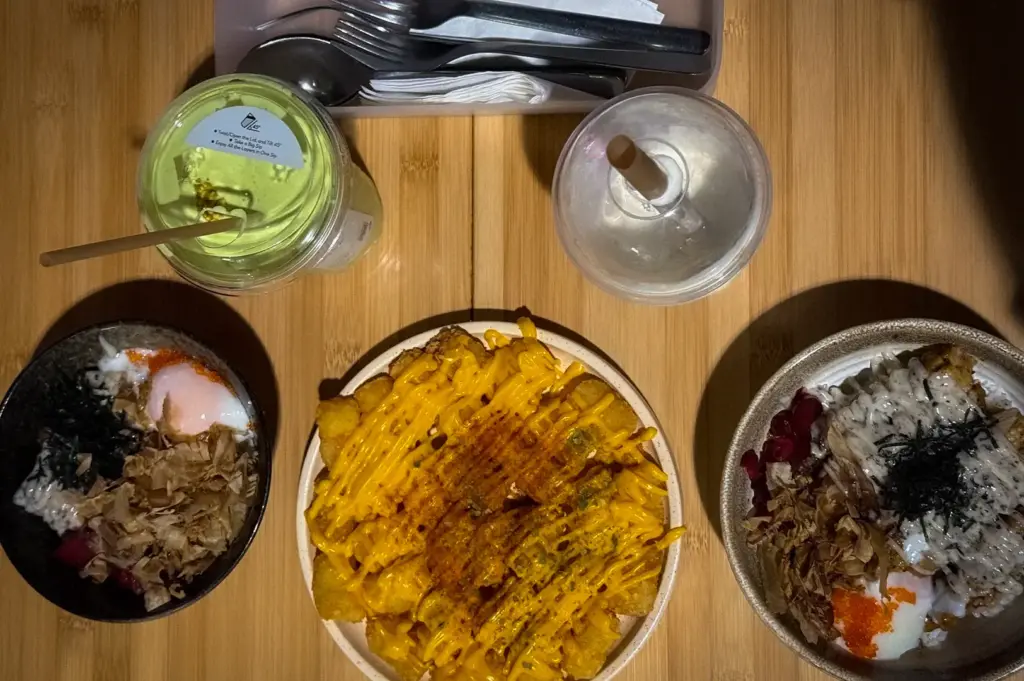 FYP Cafe Singapore food spread with loaded fries, rice bowls, matcha drink, and condiments served on a wooden table.