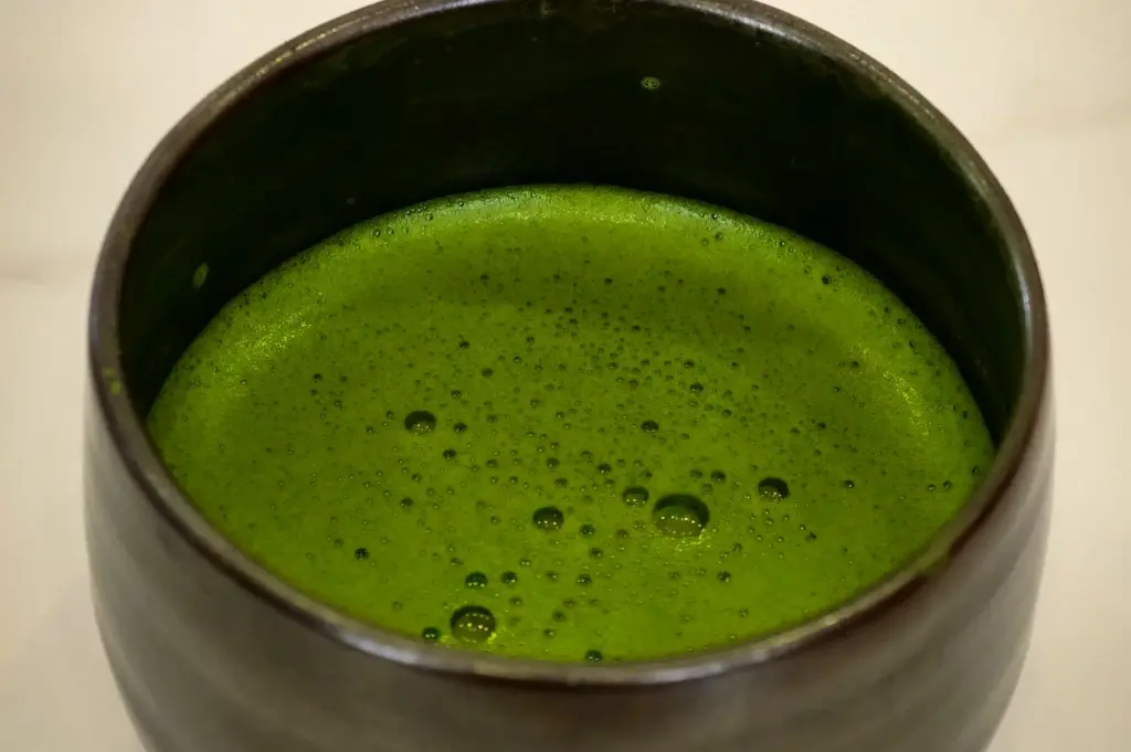 Frothy ceremonial Japanese whisked matcha green tea served in a dark ceramic chawan bowl at Hvala 111 Somerset.
