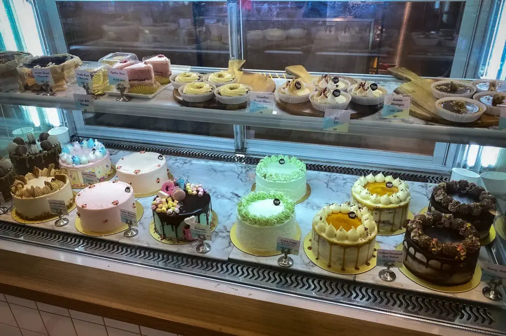 Refrigerated glass display shelf showcasing artisan tarts, cake slices, and whole decorated celebration cakes at Butter Studio in Bugis Junction, Singapore