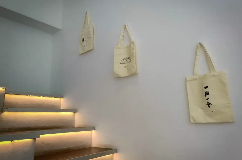Minimalist white wall and illuminated staircase decorated with canvas tote bags at Hvala 111 Somerset.