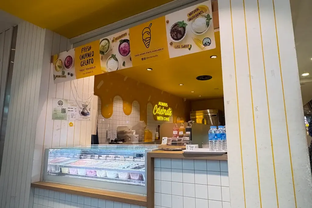 Storefront view of the fresh-churned gelato counter with yellow ceiling accent walls and white tiled pillars at Butter Studio in Bugis Junction, Singapore