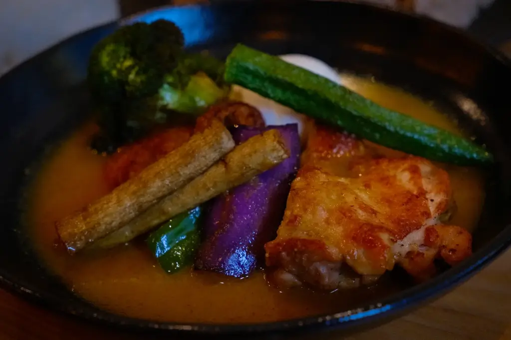 Hokkaido soup curry with crispy chicken, broccoli, zucchini, eggplant, green pepper, and root vegetables.
