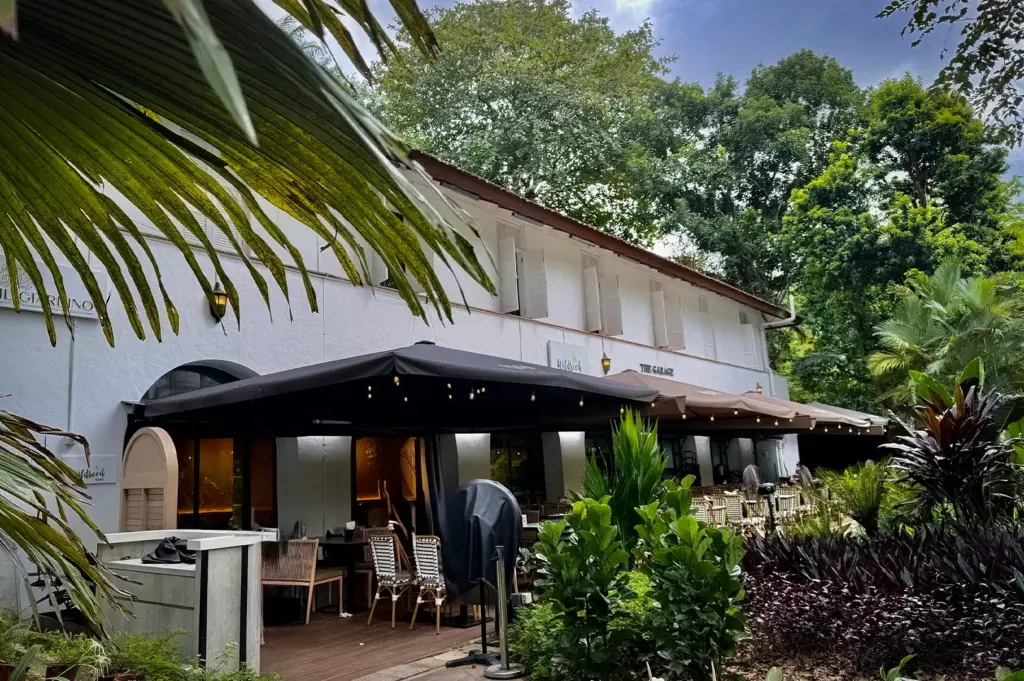 Wildseed Café exterior near the Botanic Gardens featuring a white two-story building facade with outdoor patio seating under black awnings surrounded by lush greenery