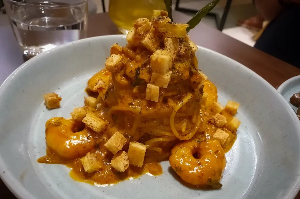 Plate of creamy prawn pasta topped with crunchy croutons and garnished with fresh herbs at Acoustics Coffee Bar in Singapore