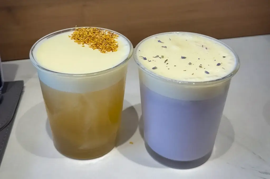 Two iced specialty beverages topped with thick cream foam and dried floral garnishes served at Acoustics Coffee Bar in Singapore